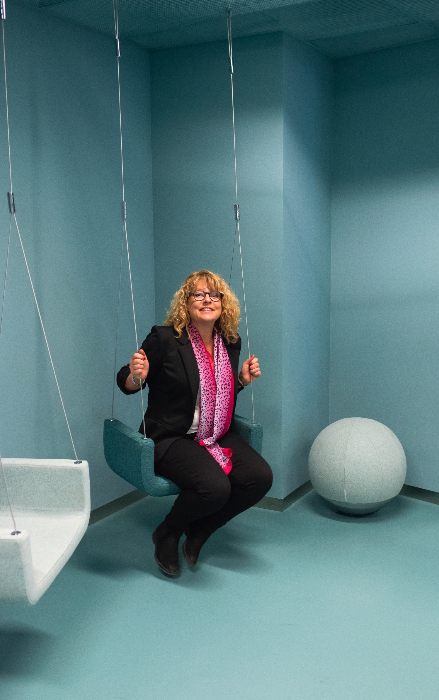 Kvinna som sitter på en gunga i ett turkost rum