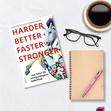 Bild på en bok, glasögon, penna och kaffekopp på ett bord